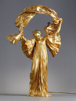 une statue en or représentant une femme tenant une fleur dans ses mains