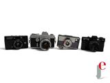 three old cameras are lined up in a row on a white surface