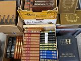 de nombreux livres rangés dans des cartons posés sur une table dans une pièce
