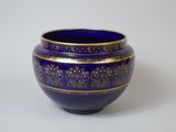 un vase bleu orné de motifs dorés sur un fond blanc