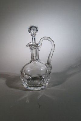 a clear glass bottle with a handle on a table