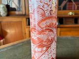 a red and white vase sitting on top of a table