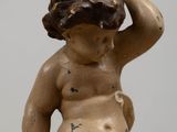 a small statue of a child holding a bottle on his head