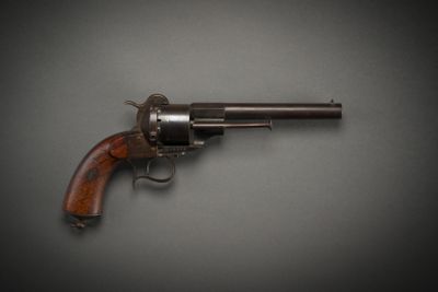 un gros plan d'un revolver posé sur une table, sur fond gris