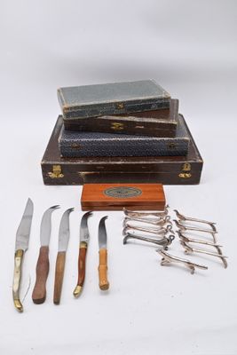 cinq types de couteaux différents et un livre posés sur une table