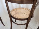 a wooden chair with a wicker seat on a white sheet