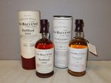 trois bouteilles de whisky posées sur une table à côté d'un bidon