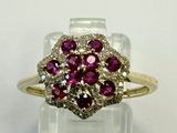 a close up of a diamond and ruby ring on a clear surface