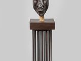 un gros plan d'une sculpture représentant une tête de lion posée sur un socle en bois