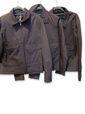 three brown jackets hanging on a clothes rack on a white wall