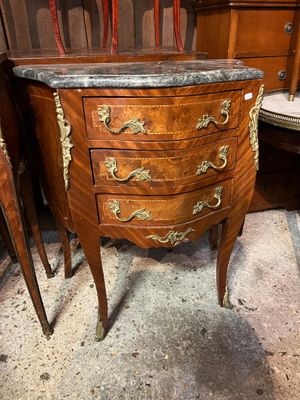 a marble top chest of drawers in the corner of a room