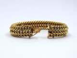 a close up of a gold bracelet on a white surface