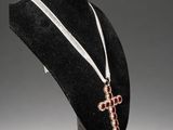 a close up of a necklace on a mannequin with a cross on it