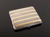 a close up of a silver and gold striped business card case