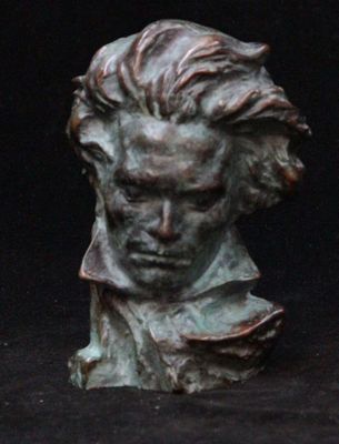 bronze bust of a man with long hair on a black background