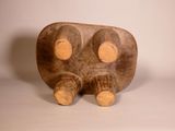 a wooden sculpture of a bear sitting on a white surface