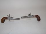 pair of antique pistols with wooden grips on display on a white surface