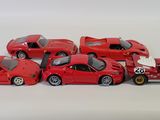 six red toy cars lined up on a white surface