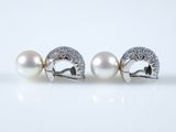 a pair of pearl and diamond earrings on a white surface