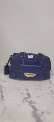 sac à main en cuir bleu posé sur une surface en marbre, sur fond blanc