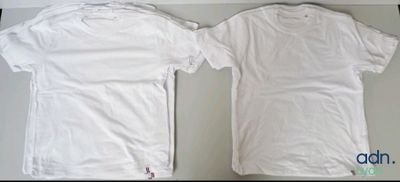 two white t - shirts sitting on top of a table next to each other