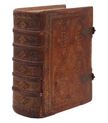 un vieux livre relié en cuir, orné de motifs élaborés sur la couverture et les tranches