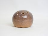 a brown vase with holes in it sitting on a white surface