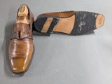pair of men ' s shoes on a grey surface with one shoe on the ground