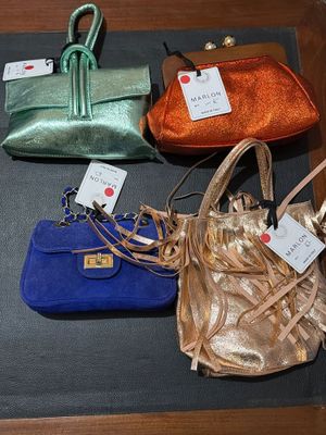 three purses sitting on a table with tags on them