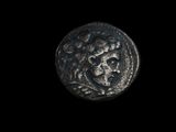 l'image d'une pièce de monnaie sur laquelle figure un visage, sur fond noir