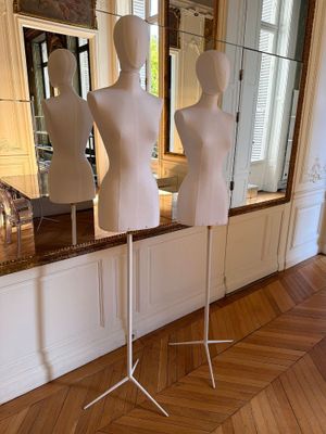 trois mannequins posés sur un socle devant un miroir