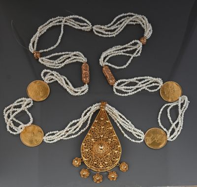 an image of a necklace with coins and a pendant on a table