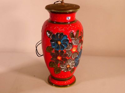 a red vase with flowers painted on it on a table
