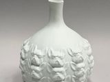 a white vase that has a bunch of flowers on it