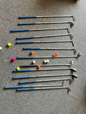 de nombreux clubs et balles de golf éparpillés sur le sol