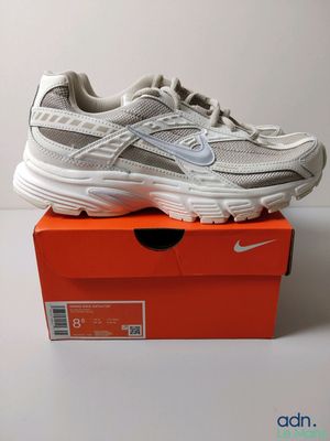 une paire de baskets blanches posée sur une boîte rouge