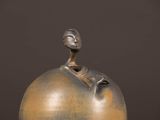 a bronze sculpture of a man sitting on top of an apple