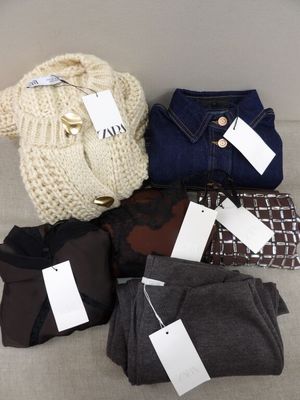 quatre paires de pulls pour femme, encore étiquetés, posés sur un canapé