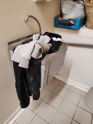 un lavabo dans une salle de bains sur lequel sont suspendus de nombreux vêtements