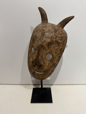 an image of a wooden mask with horns on a black stand