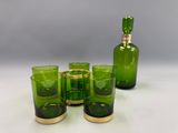 quatre verres verts et une bouteille verte sur une table blanche