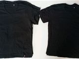 two black t - shirts sitting next to each other on a table