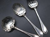 three silver spoons and a fork on a black surface