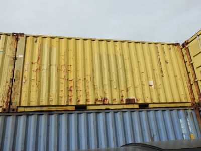 yellow and blue shipping containers stacked on top of each other in a parking lot