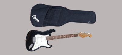 une guitare électrique noire et un étui noir sur fond gris