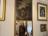 tableau accroché au mur au-dessus d'un miroir, dans une pièce où sont accrochées des photos aux murs