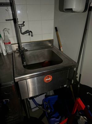 un évier dans un coin de la cuisine, avec un seau contenant des produits d'entretien