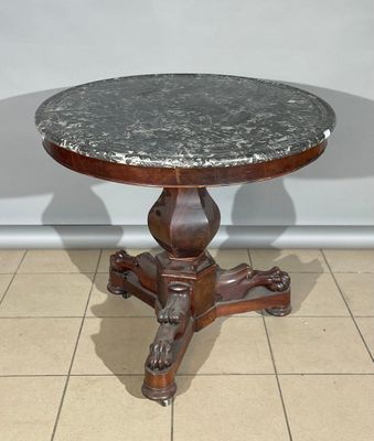 une table ancienne au plateau en marbre et au piètement en bois, posée sur un sol carrelé
