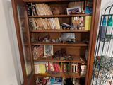 a wooden bookcase with books and a chair in the corner
