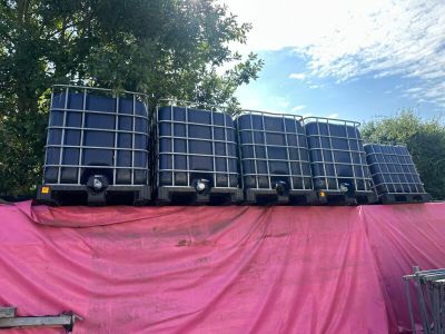 a lot of water tanks sitting on top of a pink tarp